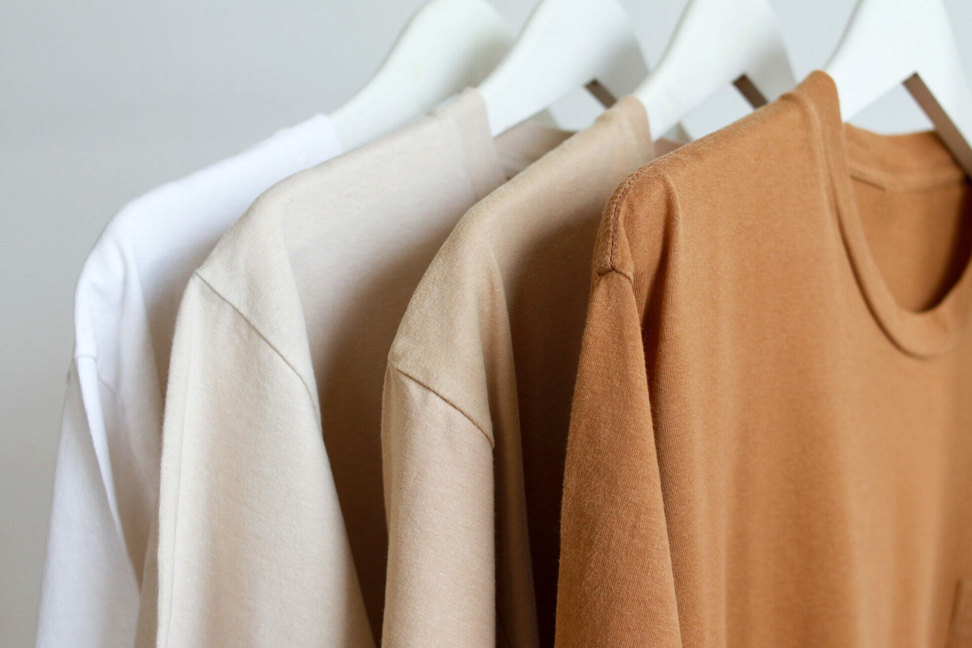 Row of brown t-shirts colors variant hanging on white hanger on rack clothes Row of brown t-shirts colors variant hanging on white hanger on rack clothes